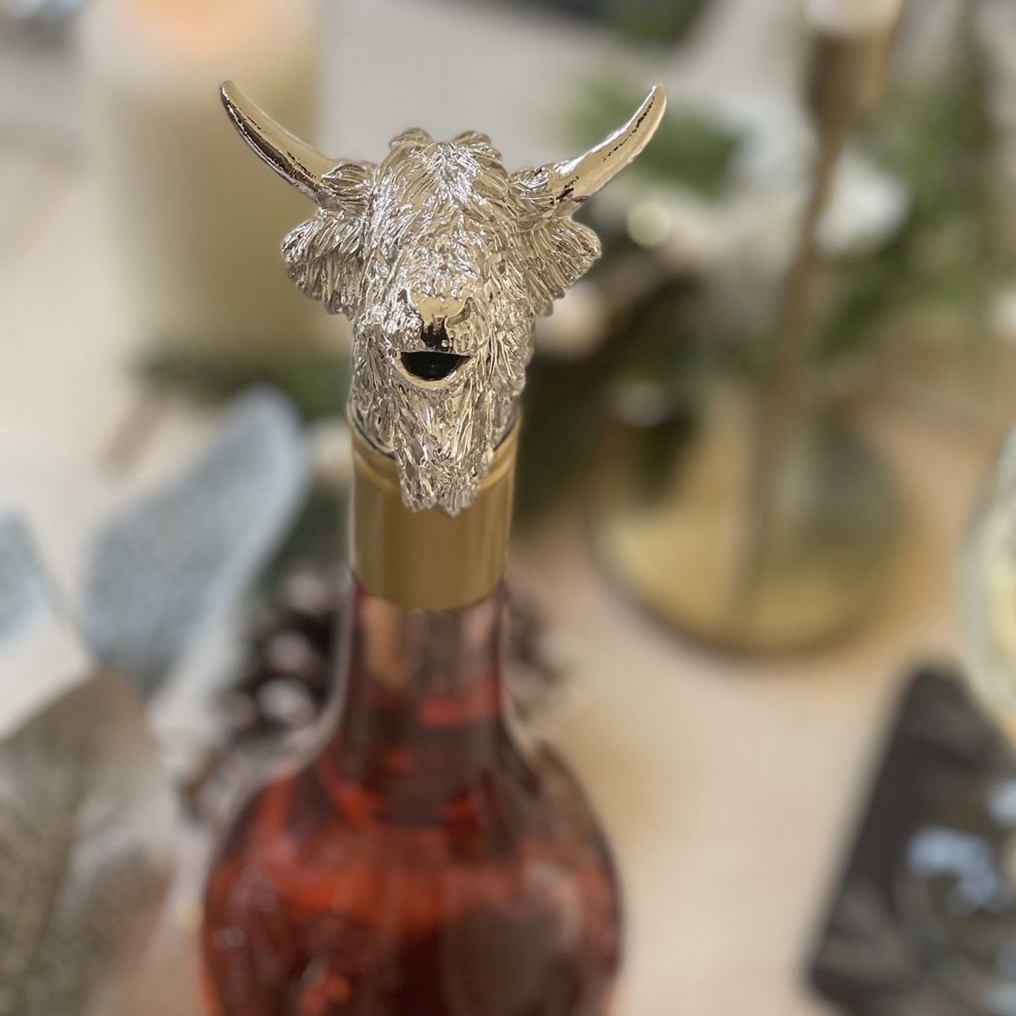 A wine pourer with silver Highland cow head on a wine bottle