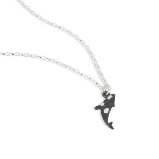 A silver necklace with a dark oxidised Orca charm