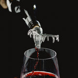 A wine pourer with silver stag head pouring red wine