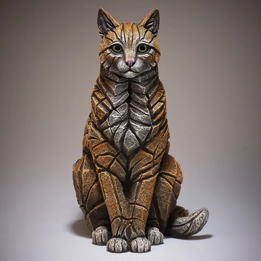 Front view of a modern sculpture of a sitting ginger cat with white chest and toes