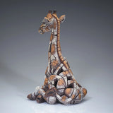 Back view of a modern sculpture of a sitting giraffe calf