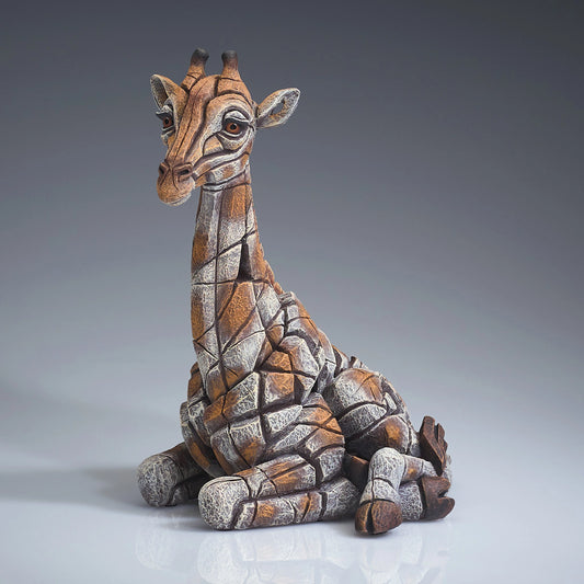 Side view of a modern sculpture of a sitting giraffe calf