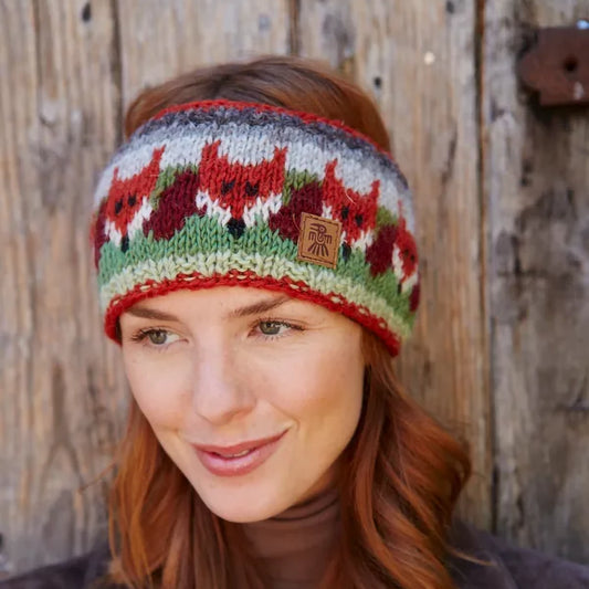 Model wearing a knitted headband featuring a row of orange fox faces and tails