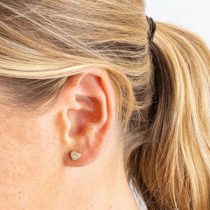 Model wearing gold heart shaped stud earrings with CZ stones