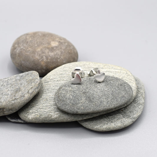 A pair of small silver earrings shaped like hearts