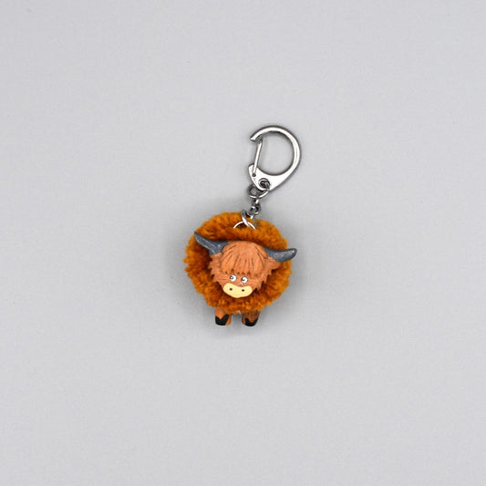 A pompom Highland cow keyring with wooden head and legs