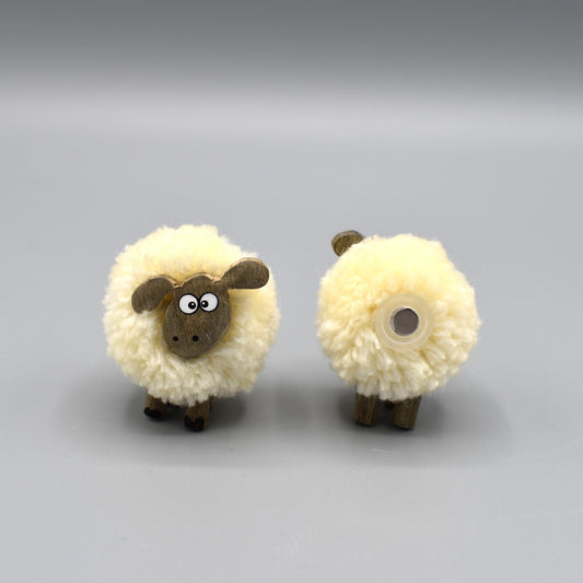 A pompom sheep magnet with wooden face and legs