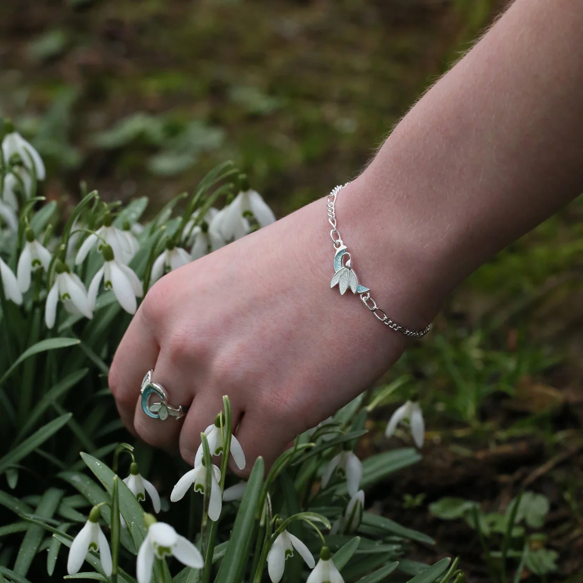 Silver chain link bracelet with enamel snowdrop pendant on model