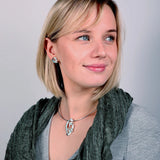 Model wearing a silver snowdrop necklet with matching stud earrings in green and white enamel