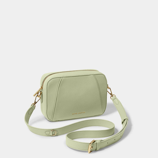 A soft sage crossbody bag in a simple box shape with adjustable strap and gold hardware