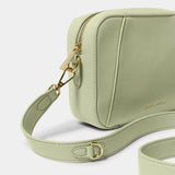 Detail of soft sage crossbody bag in a simple box shape with adjustable strap and gold hardware