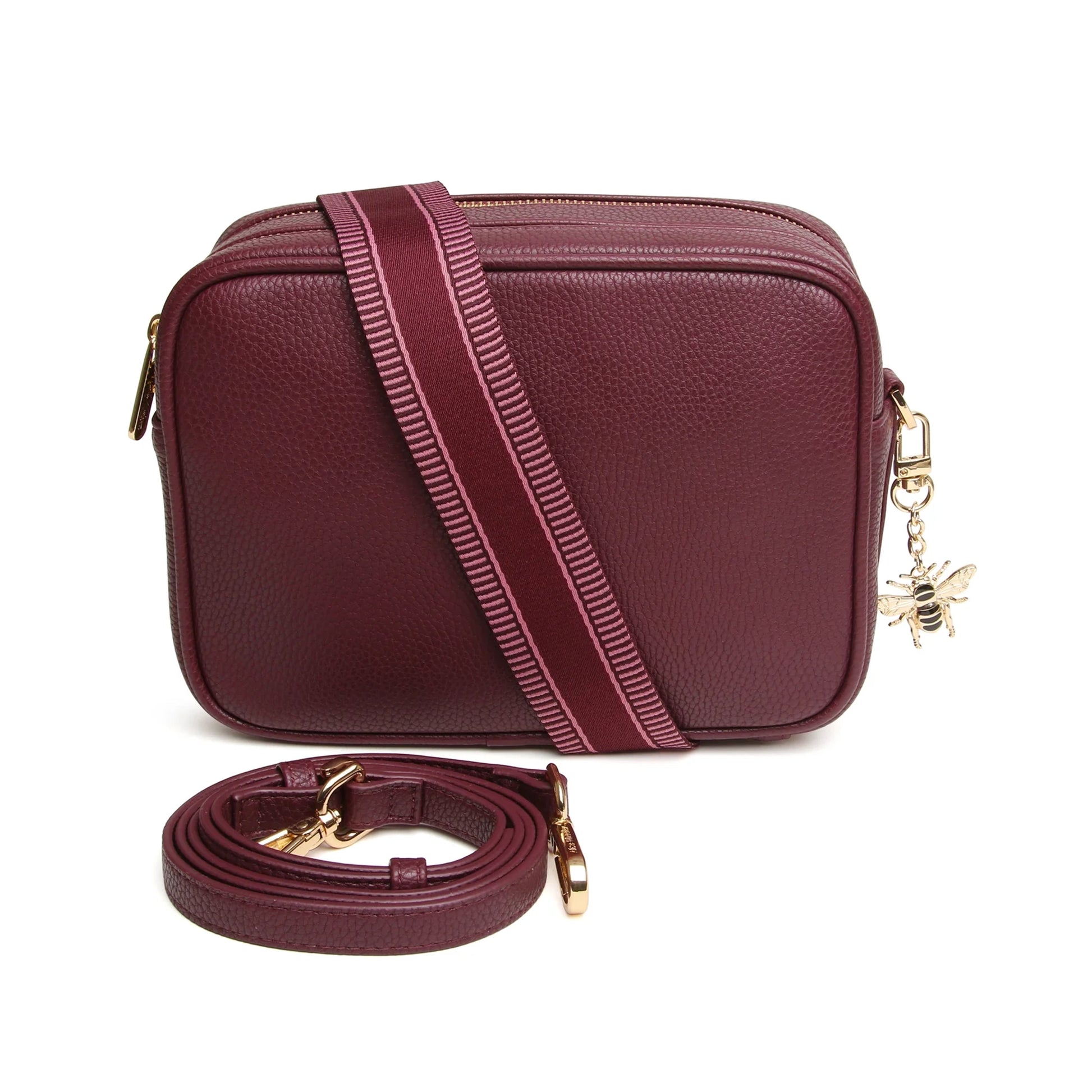 A berry red faux leather cross body bag with two straps and one leather, one patterned canvas