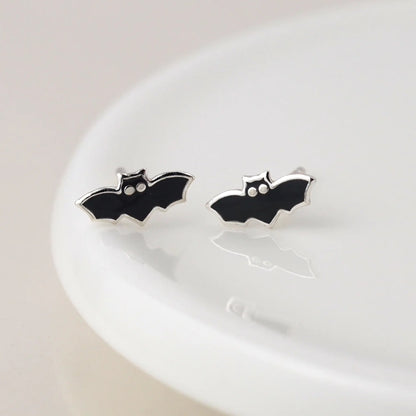 Pair of silver stud earrings shaped like bats with enamelled details