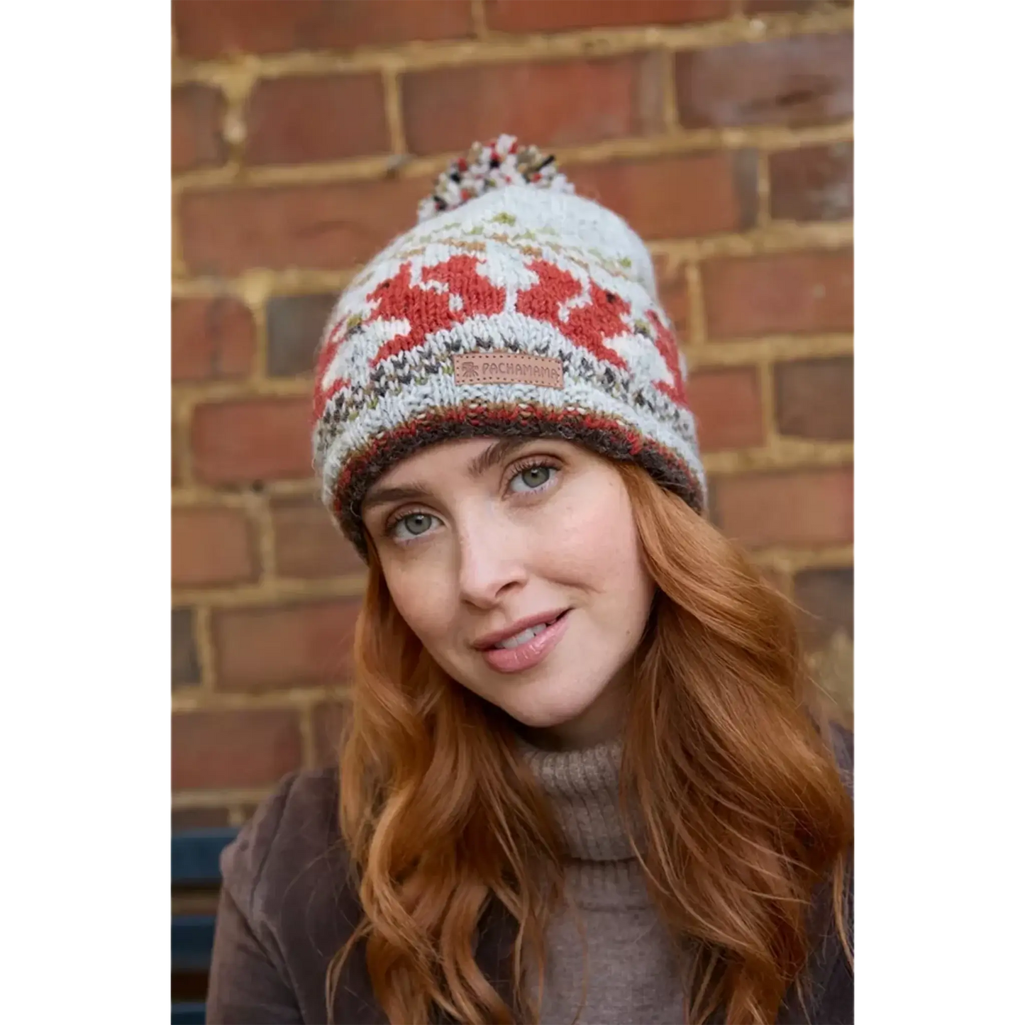 Model wearing a knitted beanie bobble hat with a squirrel fair isle pattern