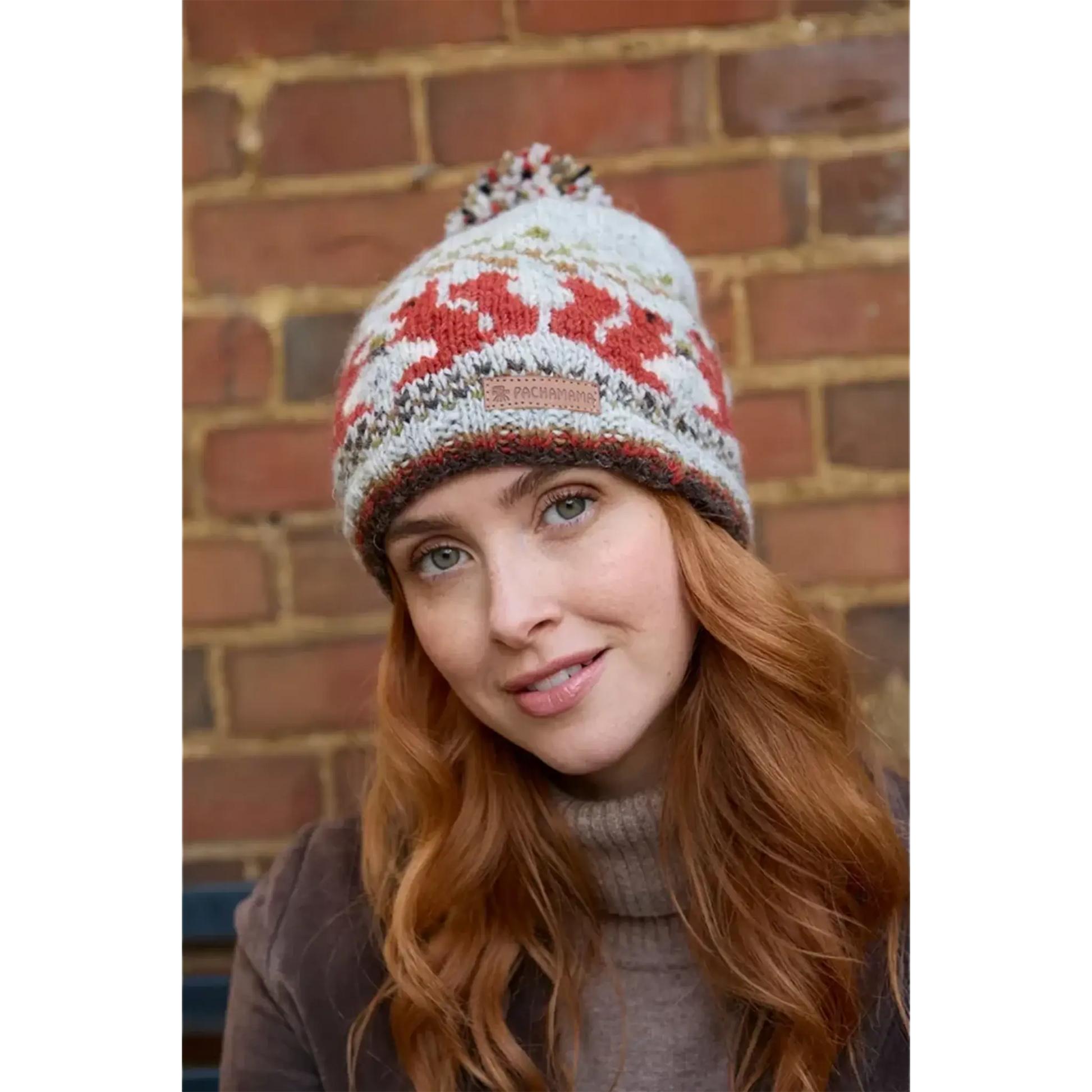 Model wearing a knitted beanie bobble hat with a squirrel fair isle pattern