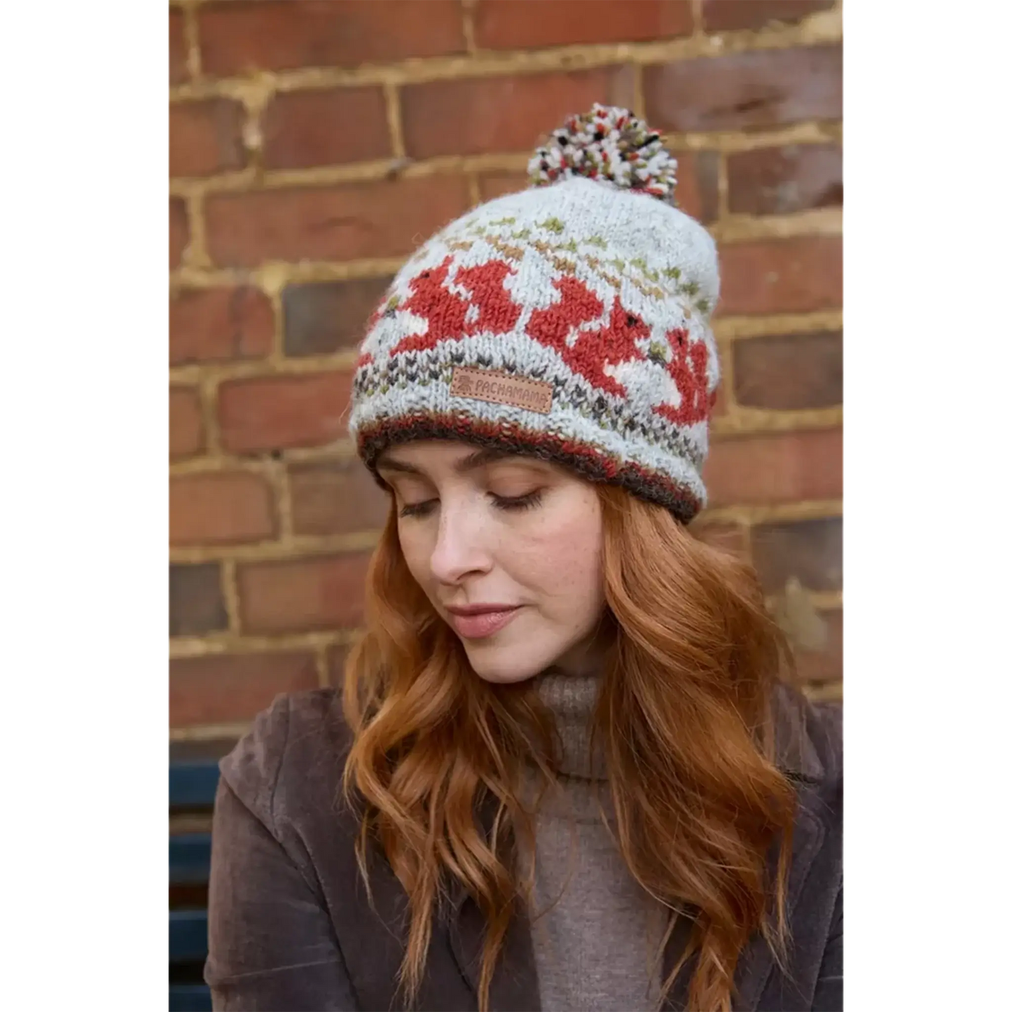 Model wearing a knitted beanie bobble hat with a squirrel fair isle pattern