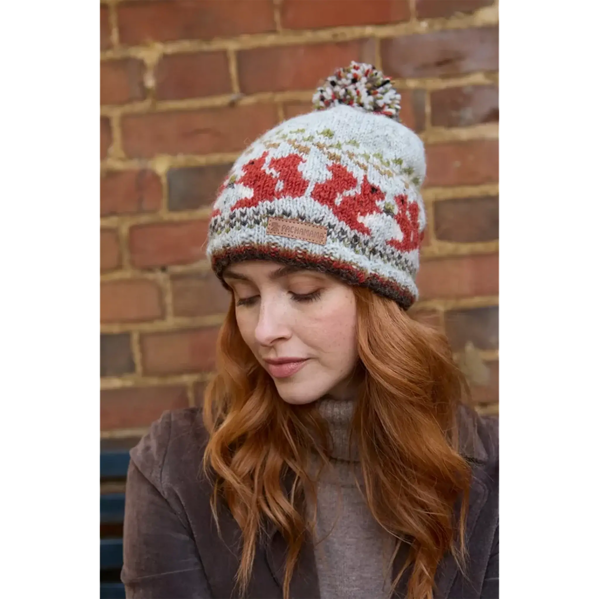 Model wearing a knitted beanie bobble hat with a squirrel fair isle pattern