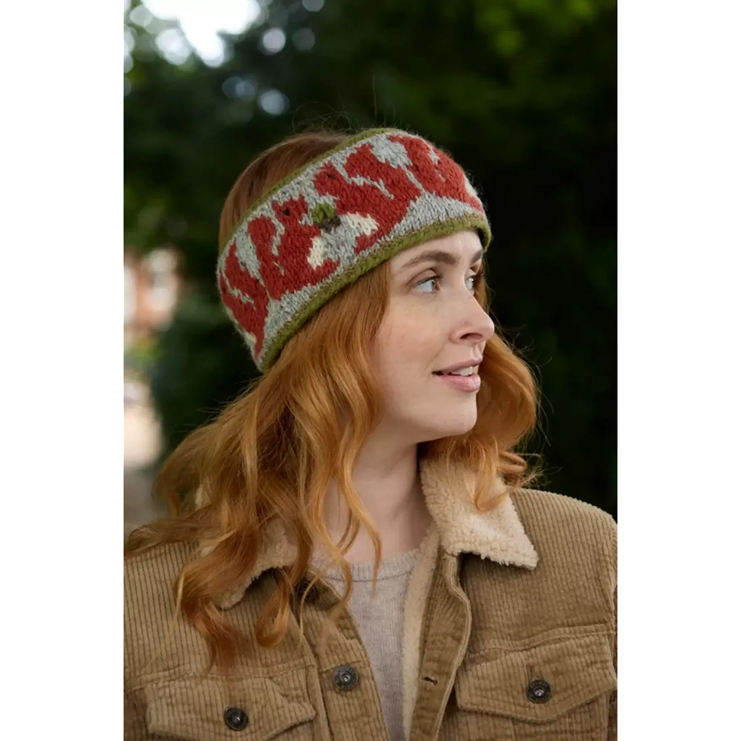 Model wearing knitted headband with row of red squirrels and acorn pattern