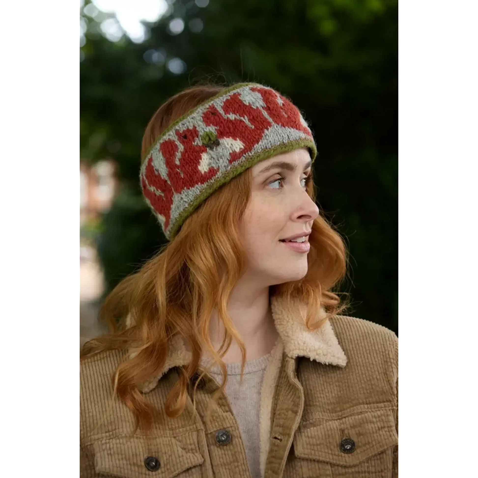 Model wearing knitted headband with row of red squirrels and acorn pattern