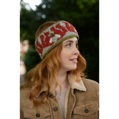 Model wearing knitted headband with row of red squirrels and acorn pattern