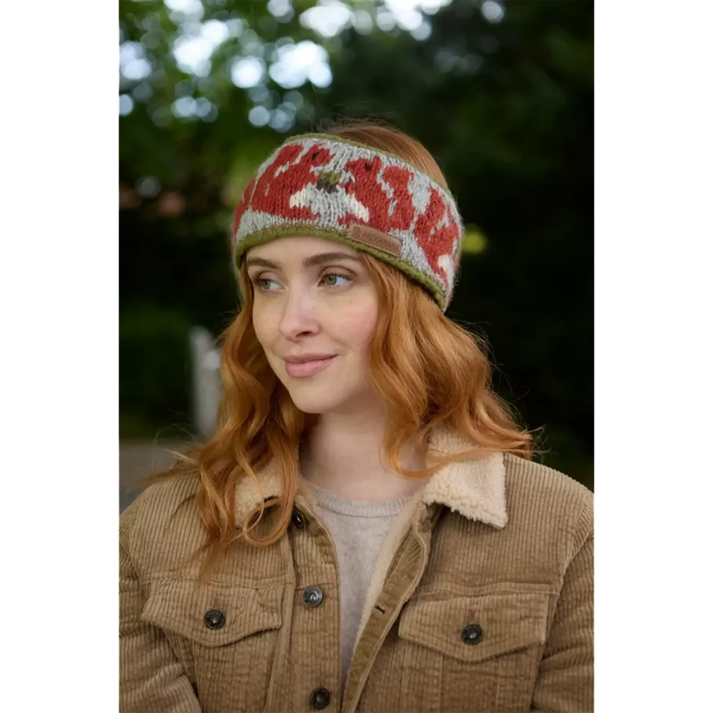 Model wearing knitted headband with row of red squirrels and acorn pattern