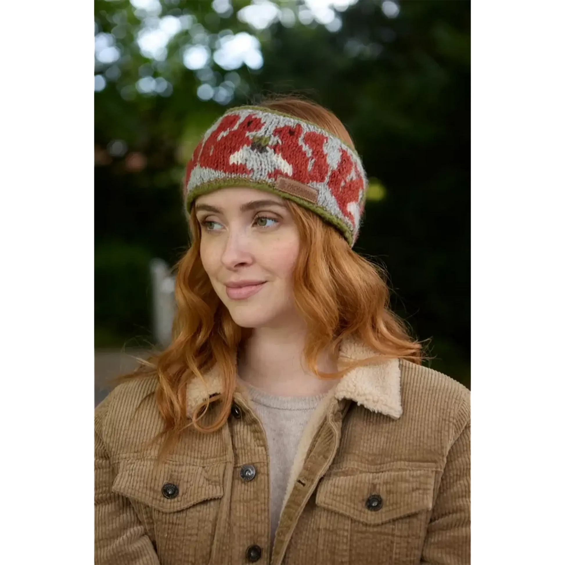 Model wearing knitted headband with row of red squirrels and acorn pattern