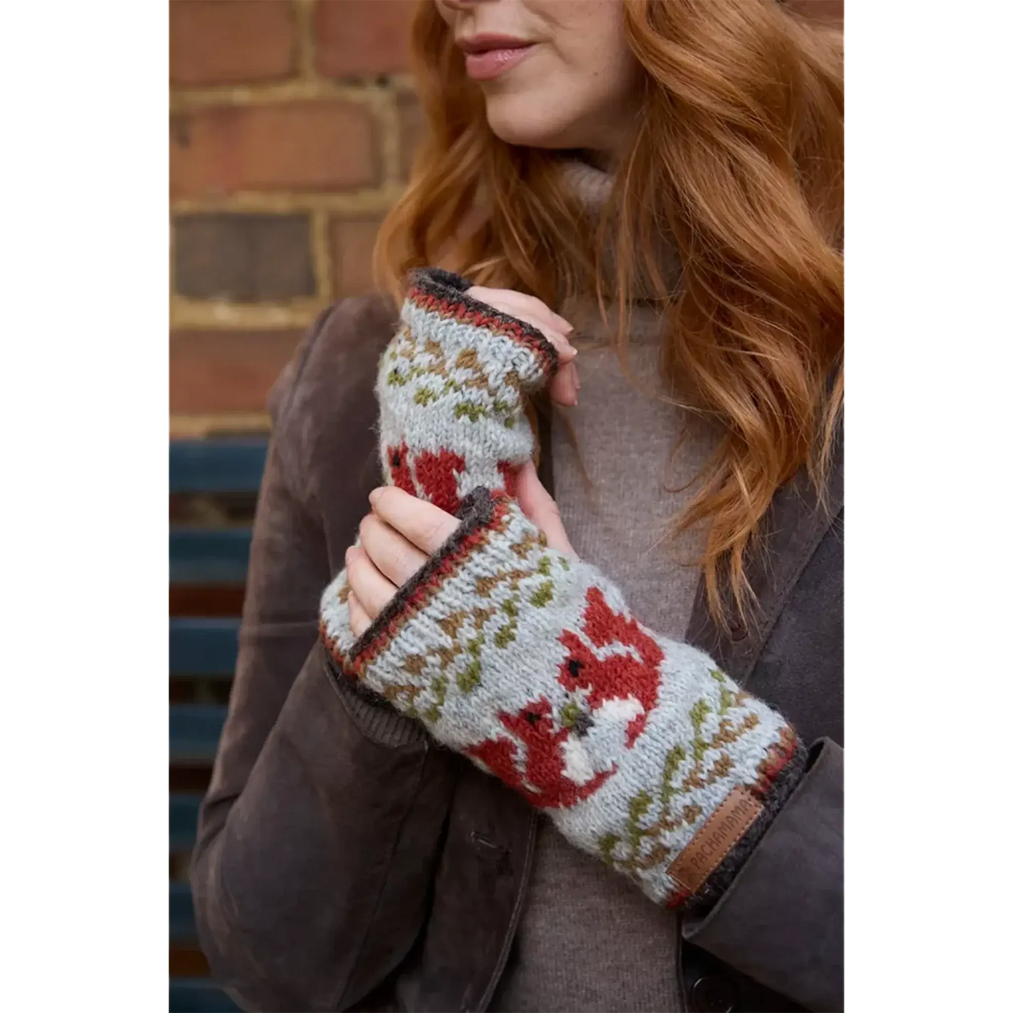 Model wearing knitted handwarmers with fair isle style red squirrel pattern