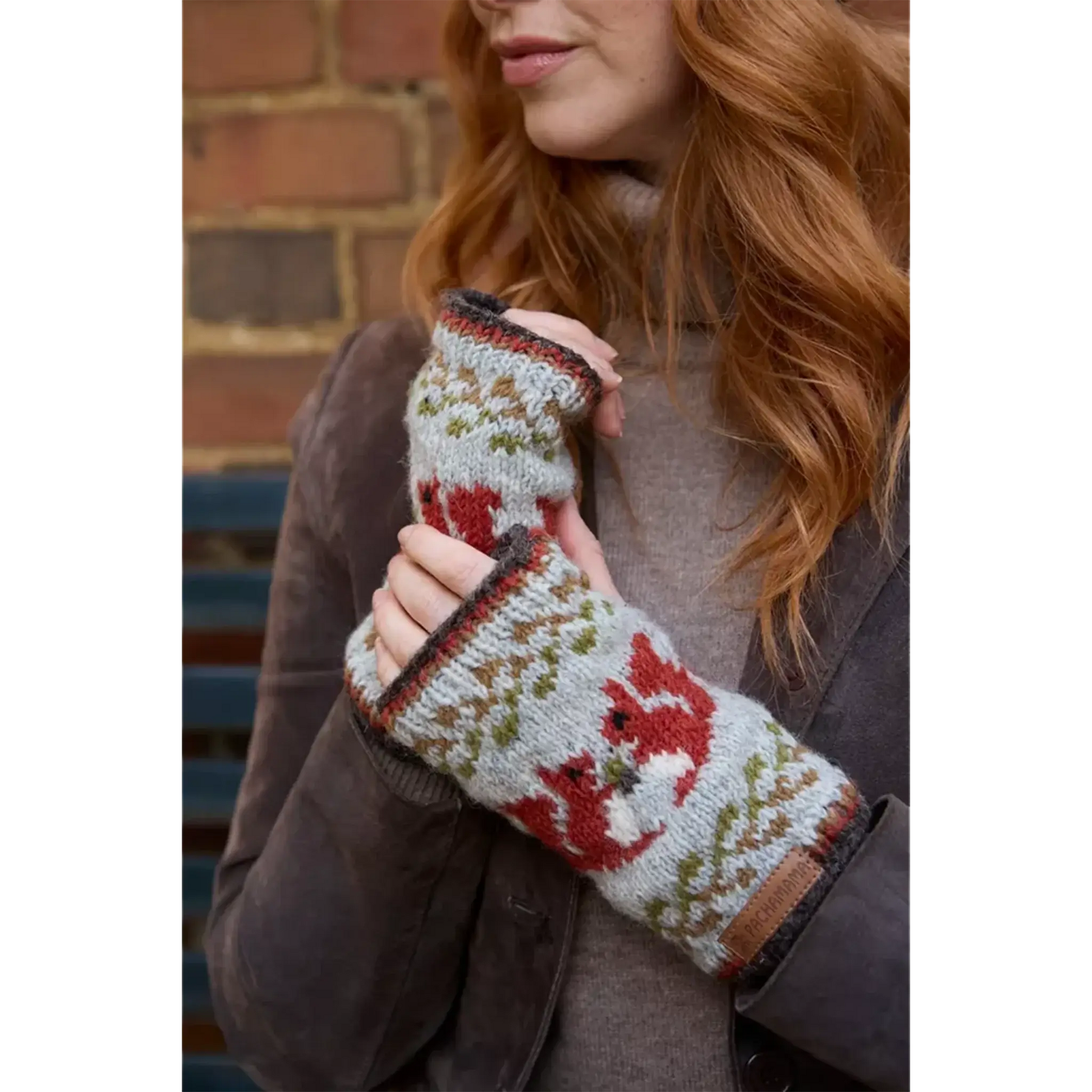 Model wearing knitted handwarmers with fair isle style red squirrel pattern