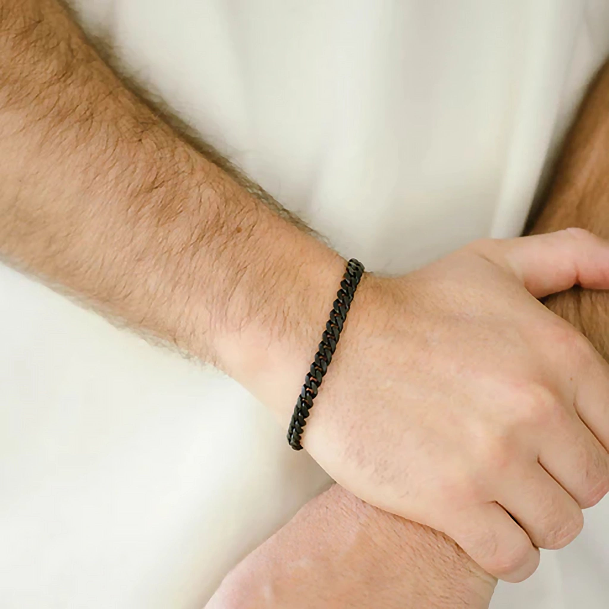 Model wearing a matt black coated stainless steel chain bracelet with monogramed clasp