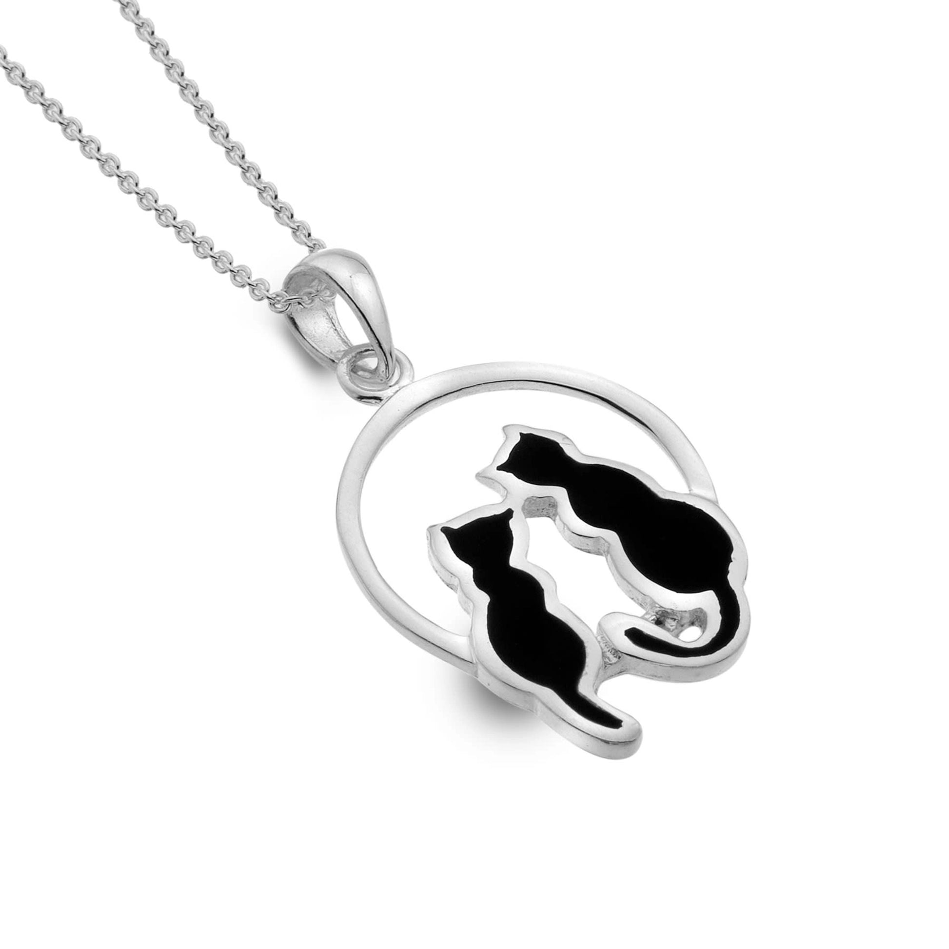 A silver pendant featuring a round frame with two sitting black cats