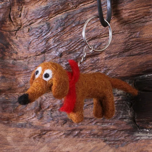 A brown felted sausage dog keyring with a red bow