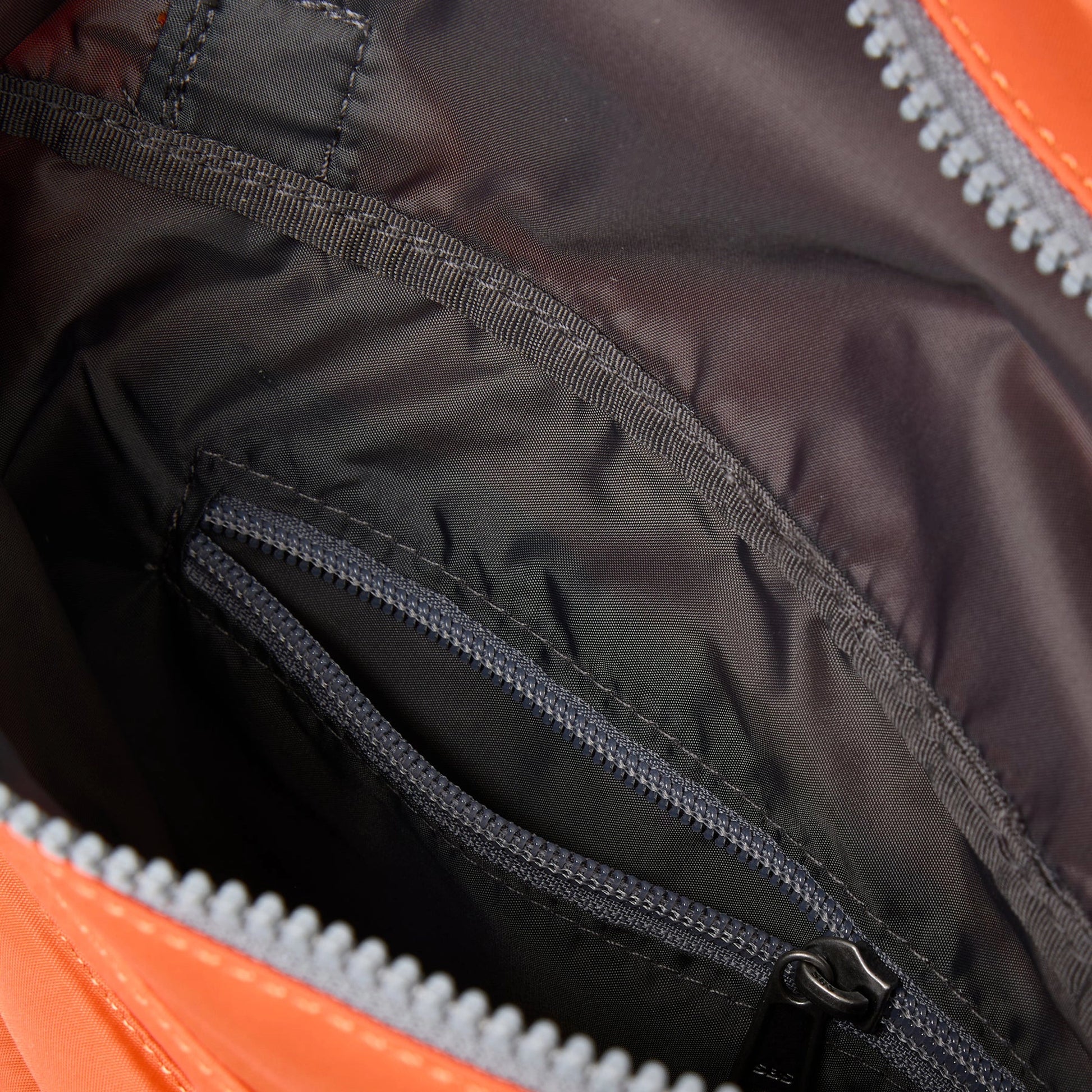 A square orange nylon bag with grey cotton and internal zip pocket