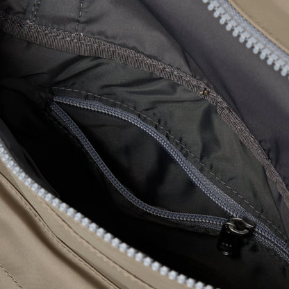 A square taupe nylon bag with grey cotton strap and roll top with internal zip pocket