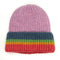 A knitted beanie hat in lilac with a ribbed rainbow striped turn up