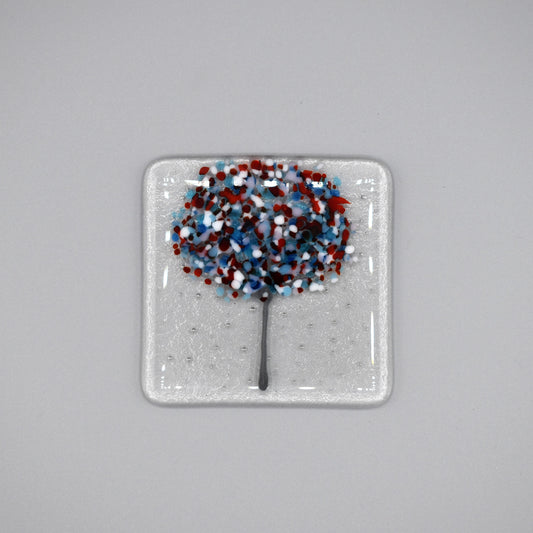 A clear glass square coaster with a blue & red tree design