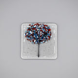 A clear glass square coaster with a blue & red tree design