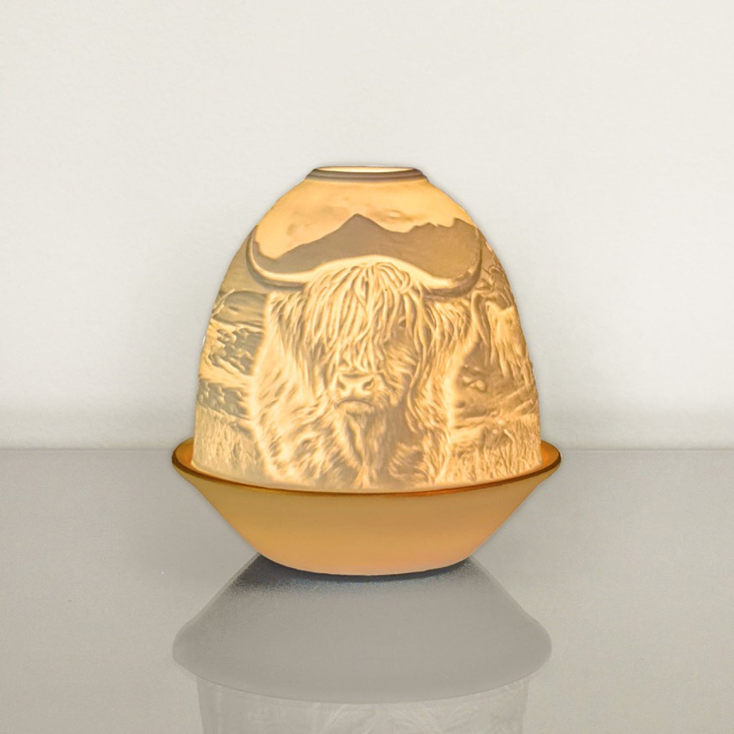 White porcelain tall dome candle holder with engraved Highland cow and gold rimmed plate lit up