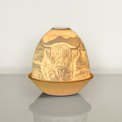 White porcelain tall dome candle holder with engraved Highland cow and gold rimmed plate lit up