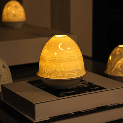 White porcelain tall dome candle holder with engraved starry night scene and gold rimmed plate lifestyle