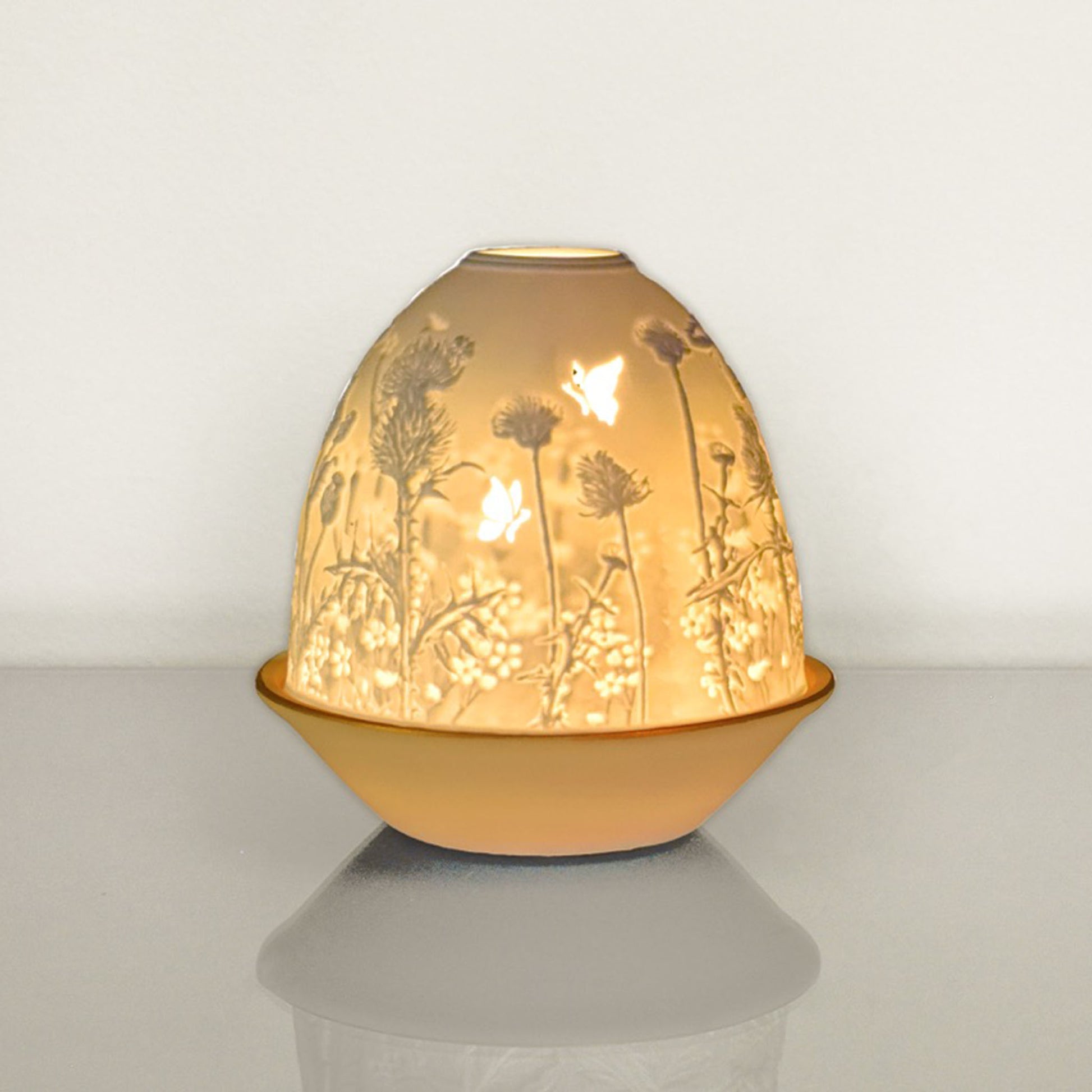 White porcelain tall dome candle holder with engraved thistle scene and gold rimmed plate lit up