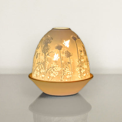 White porcelain tall dome candle holder with engraved thistle scene and gold rimmed plate lit up