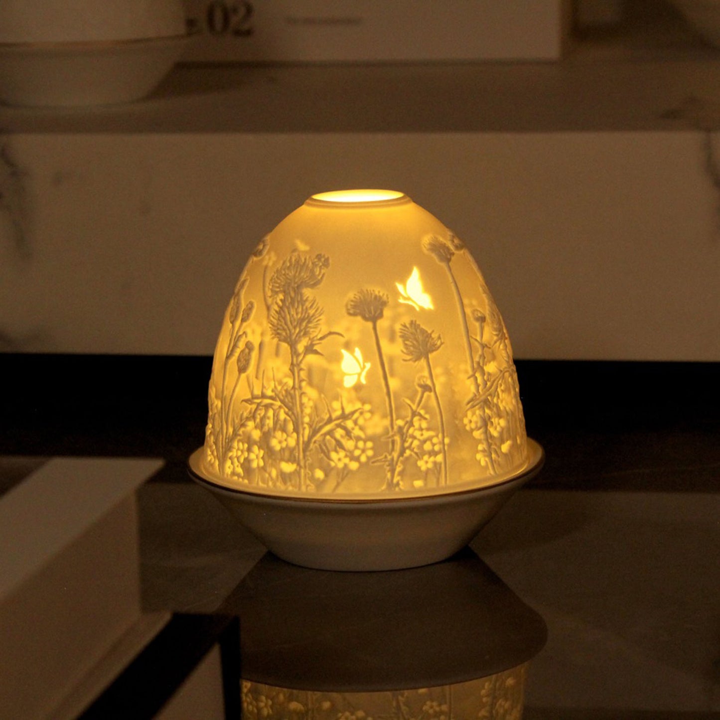 White porcelain tall dome candle holder with engraved thistle scene and gold rimmed plate lifestyle