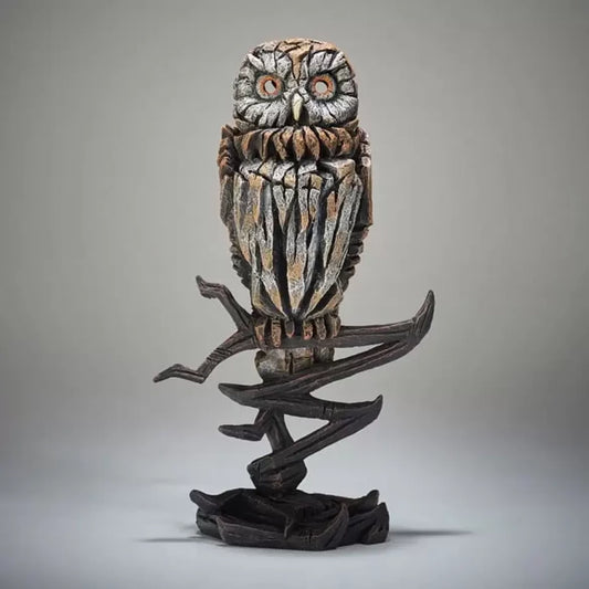A textured and painted tawny owl perched on a branch figure sculpture