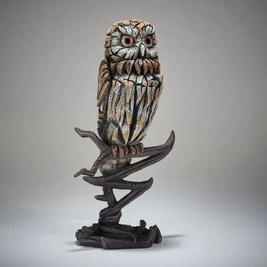 A textured and painted tawny owl perched on a branch figure sculpture side view