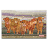 A tea towel with an illustration of a herd of Highland cows on a felted landscape background