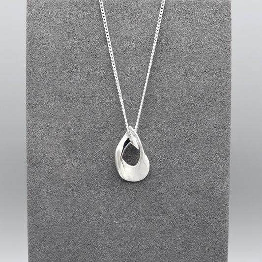 A silver pendant shaped like an open twisted teardrop with a matt and shiny finish