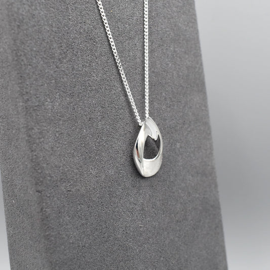 A silver pendant shaped like an open twisted teardrop with a matt and shiny finish