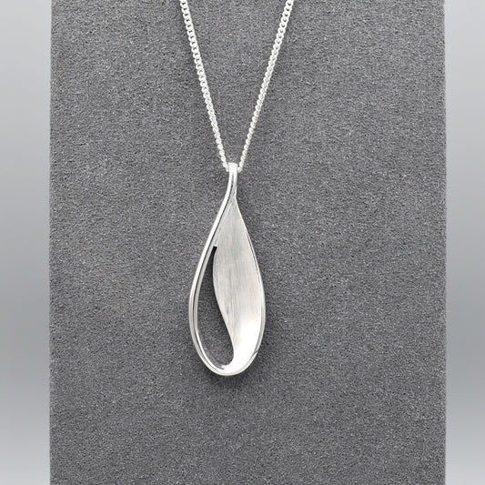 A silver teardrop leaf shaped pendant with matt texture