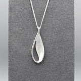 A silver teardrop leaf shaped pendant with matt texture