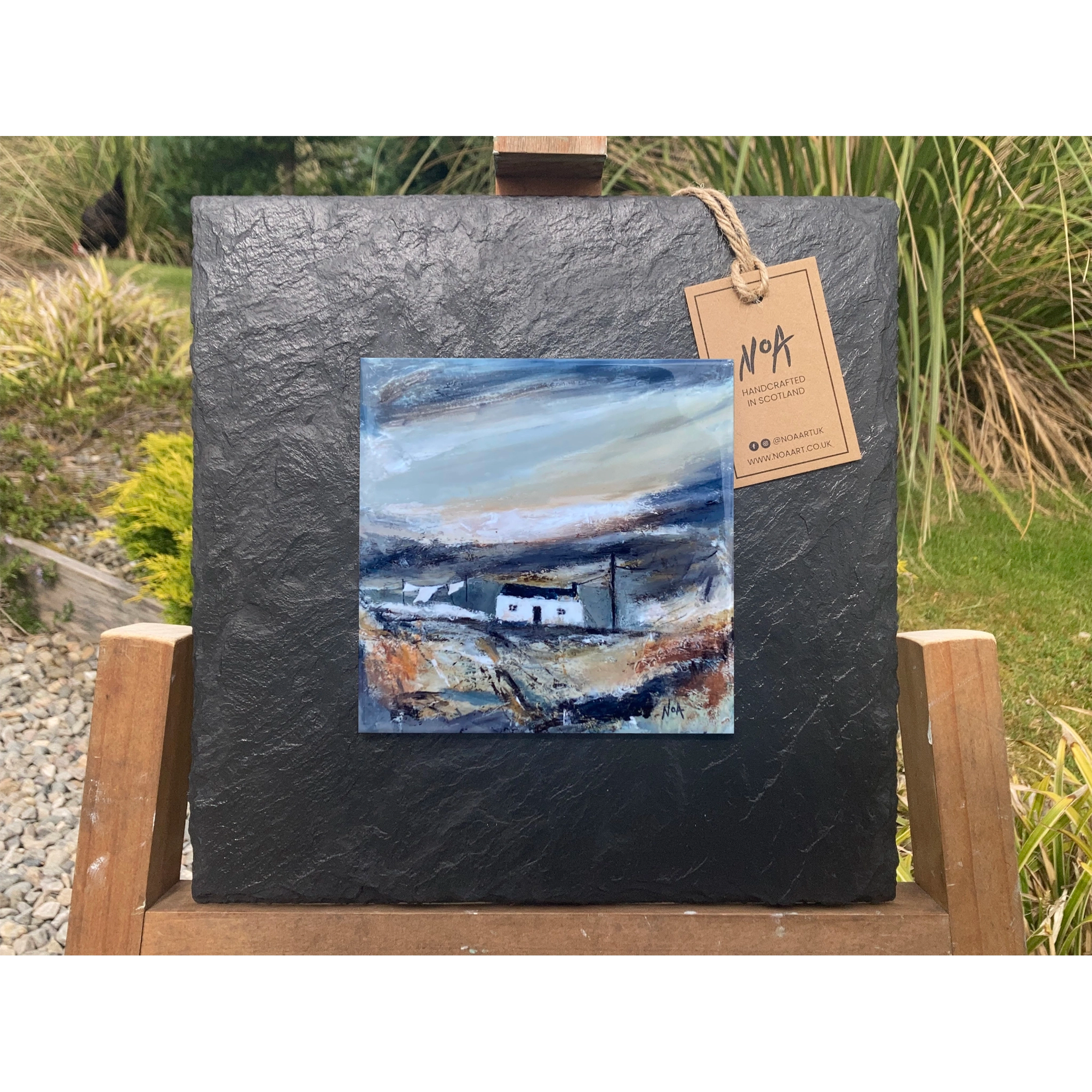 A slate mounted ceramic tile art with a white cottage and telephone pole